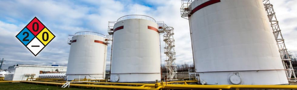 Chemical hazard sign beside large tanks